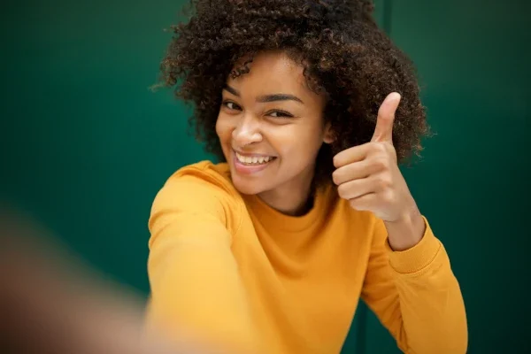 mulher jovem sorrindo com o polegar para cima